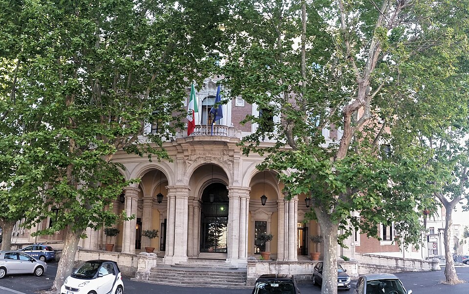 プラタナスの並木の奥に見える、国旗を掲げたローマの交通省の正面玄関